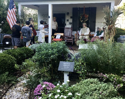 Gardens at the Colonial House with guests in the background listening to a historian